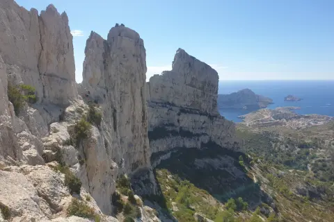Vue spectaculaire depuis le pas de la demi lune, avec des falaises calcaires imposantes dominant la mer Méditerranée et un village côtier.