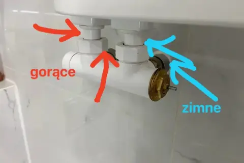 Grzejnik łazienkowy nie grzeje. Strzałki wskazują dopływ gorącej i zimnej wody do grzejnika.