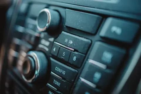 Dettaglio del pannello di un'autoradio, con manopole e pulsanti per il montaggio e la configurazione.
