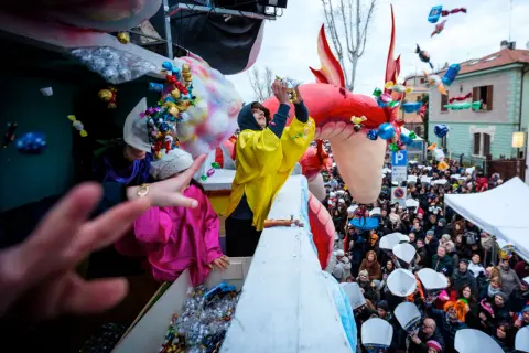 Carnevale a Fano: dolciumi volano da un carro allegorico tra la folla festante.
