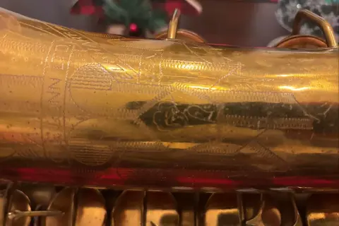 Złoty saksofon C.G. Conn z wygrawerowanym napisem i ornamentami.