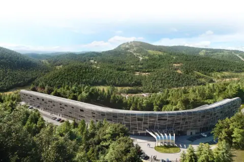 Nowoczesny, zakrzywiony budynek hotelu Mercure Szczyrk Resort otoczony lasem i górami.