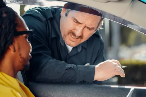 Un policier demande des papiers à un conducteur. Il espère que son nouveau permis de conduire, validité 5 ans, sera en règle.
