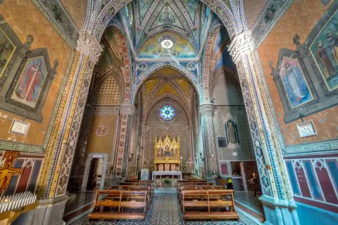 Interno di un santuario in Emilia Romagna, con affreschi colorati, volte decorate e un altare dorato.