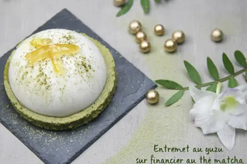 Un entremet yuzu aérien, saupoudré de matcha, repose sur un financier au thé matcha. Décoré de zestes de yuzu confits.