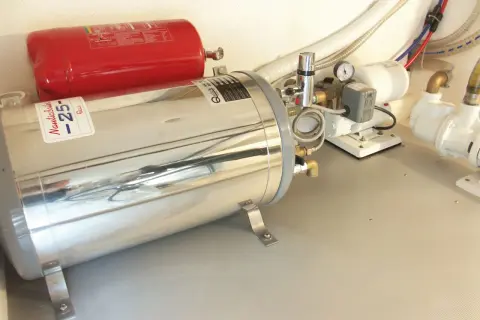 Boiler nautico in acciaio inox e serbatoio rosso. Preparazione per svuotare boiler inverno, con pompe e tubazioni.