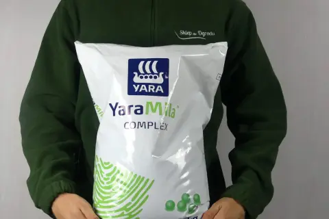 Osoba w zielonej bluzie trzyma worek nawozu YaraMila Complex o wadze 10 kg.