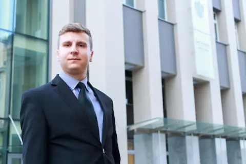 Mężczyzna w garniturze przed nowoczesnym budynkiem.