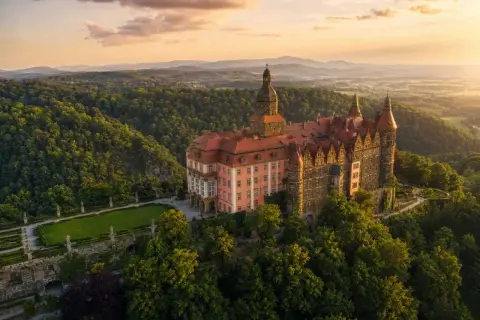 Zamek Książ, jedna z największych atrakcji Dolnego Śląska, w otoczeniu zielonych wzgórz o zachodzie słońca.