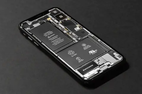 Rozłożony iPhone SE z widoczną baterią i podzespołami.