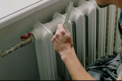 Mano che misura il detentore del termosifone con un righello.