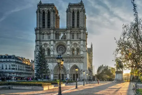 La maestosa cattedrale di Notre Dame de Paris, con le sue torri imponenti e un albero di Natale illuminato, si erge maestosa sotto un cielo nuvoloso.