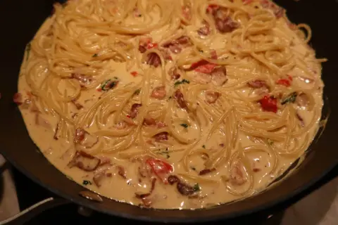 En krämig pasta med knaprigt bacon och tomater i en panna. Enkel och god vardagsmat.