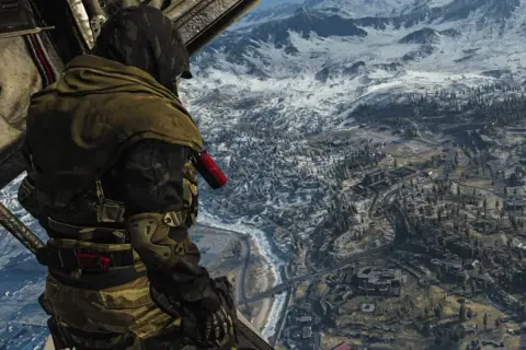 Żołnierz w kamuflażu spogląda na zimowy krajobraz Verdansk z helikoptera.