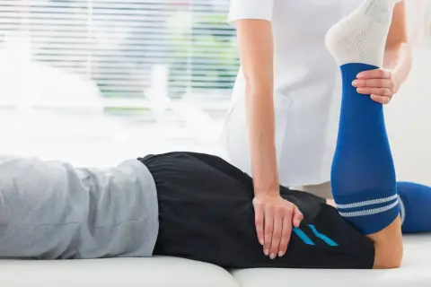 Un physiothérapeute aide un patient à étirer sa jambe pour soulager une crampe cuisse.