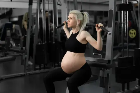 Gravid kvinna tränar rygg med latsdrag. Hon är fokuserad och stark, en inspiration för marklyft gravid.