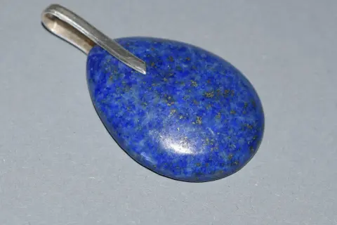 Owalny wisiorek z lapis lazuli, kamienia o intensywnie niebieskim kolorze i złotych inkluzjach. Jego właściwości od wieków cenione są w ezoteryce.