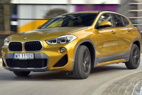 Złoty BMW F39 w ruchu, z widocznym grillem i reflektorami.