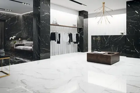 Elegancki butik z czarnymi ścianami w żyłach nero marquina i białymi podłogami. Wieszaki z ubraniami, kanapa i lada recepcyjna.