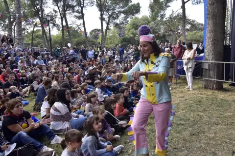 Actriz con traje colorido anima a niños en un espectáculo de marionetas en el parque.