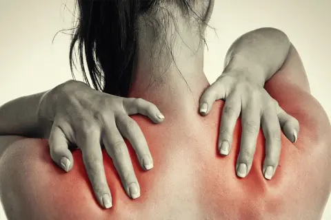 Frauenhände massieren schmerzende Schultern, die rot aufleuchten. Magnesium kann bei Hexenschuss Linderung verschaffen.