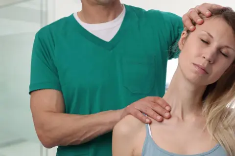 Osteopata co to? Terapeuta delikatnie masuje kark pacjentki, przynosząc ulgę w napięciu.