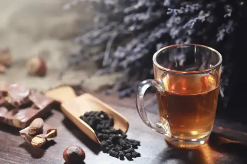 Un thé ambré dans une tasse, du chocolat, des noisettes et des feuilles de thé. Idéal pour le temps conservation thé infusé.