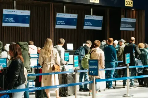 Kolejka do odprawy bagażowej. Na ekranach widnieje napis "BAGGAGE DROP-OFF", ale nie ma żadnego "no show".