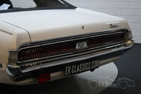 Vit cougar bil med kromdetaljer och en ikonisk grill. En klassiker som väcker nostalgi.