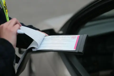 Policjant wypisuje mandat karny za wykroczenie drogowe, powołując się na art. 97 k.w. w zw. z art. 47 p.r.d.