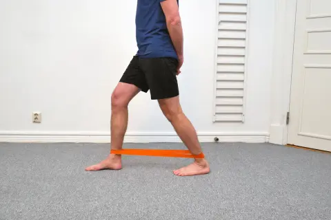 Man med orange band runt anklarna för att träna bort stela fotleder.
