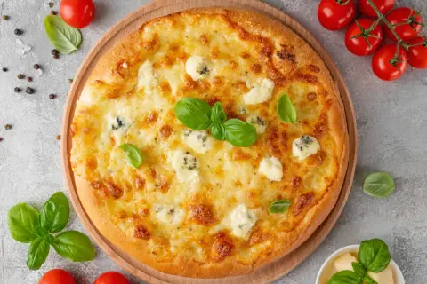 Une délicieuse pizza 4 fromages, dorée et garnie de basilic frais, prête à être dégustée.