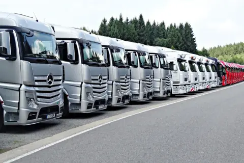 Rangée de camions Mercedes-Benz argentés et blancs, prêts pour le transport. La réglementation stationnement poids lourds est respectée.