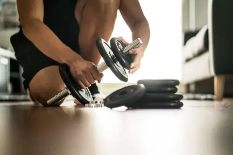 Un homme prépare ses haltères pour une séance de cardio boxing intense.