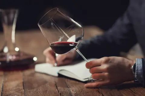 Un homme déguste un verre de vin rouge, notant ses impressions pour la saint-emilion grand cru classé liste.