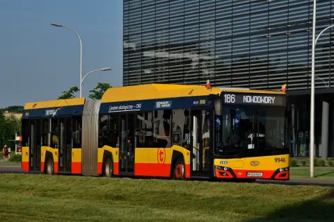 Autobus 186 linii Nowodwory w Warszawie, ekologiczny, zasilany CNG, stoi na tle nowoczesnego budynku.