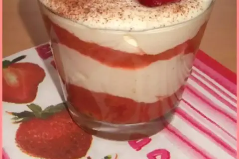 Un délicieux tiramisu rhubarbe fraise, superposé en couches dans un verre, garni de fraises et de cacao.