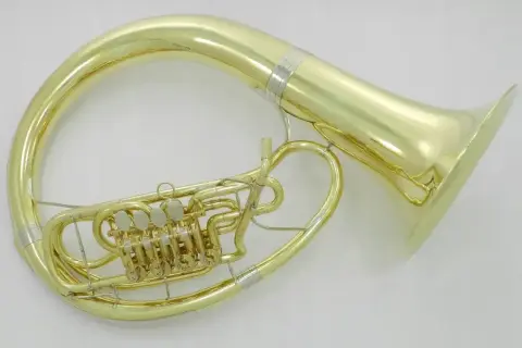 Błyszczący, złoty, duży instrument dęty z zaworami, owinięty wokół ciała muzyka, gotowy do wydobycia głębokich dźwięków.
