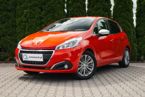 Czerwony Peugeot 208 z błyszczącymi światłami, idealny na egzamin na prawo jazdy.