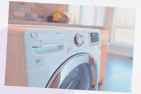 Un sèche-linge moderne dans une buanderie. Il est blanc avec une porte en verre chromé. Le panneau de commande est visible, avec un cadran et des boutons. On se demande combien de temps dure un sèche-linge pour un cycle complet.