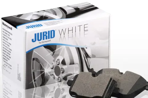 Dwa klocki hamulcowe Jurid White, wykonane z materiałów ceramicznych, leżą obok pudełka z tymi samymi klockami.