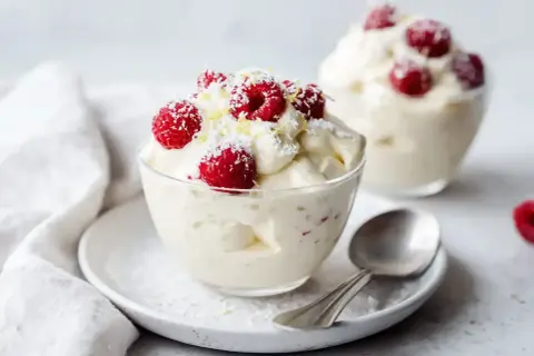 Lätt och fluffig vispad pannacotta tårta med färska hallon och kokosflingor. En perfekt sommardessert.