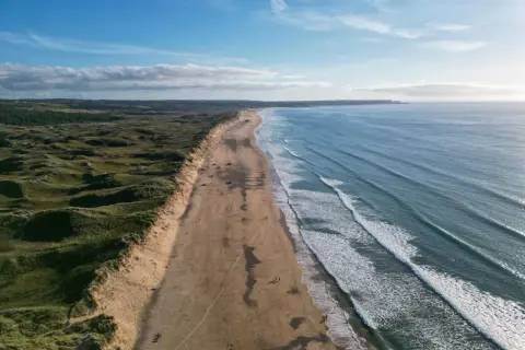 Weite Sandstrände und sanfte Dünen, ideal für mai reiseziele. Die Wellen des Ozeans laden zum Surfen ein.