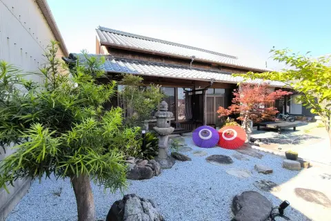 Tradycyjny dom na wyspie Japonii z Kagawa, z kamiennym ogrodem, parasolami i jesiennym drzewem klonowym.