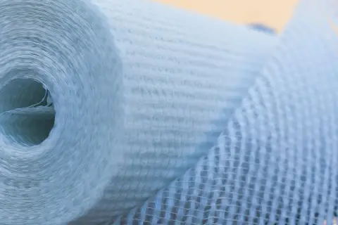 Rolle aus Glasfasergewebe, bereit zum Glasfasertapete kleben. Das Material ist hellblau und hat eine feine Netzstruktur.