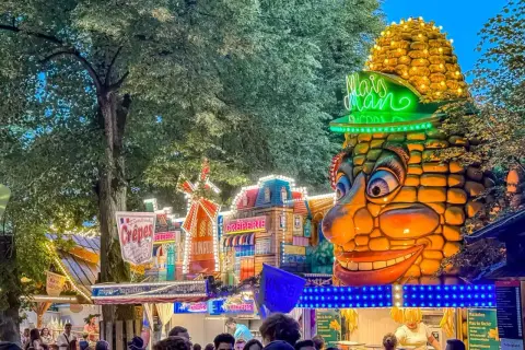 Buntes Volksfest mit Maiskolben-Figur und Buden. Das bergkirchweih erlangen programm lockt mit Leckereien.