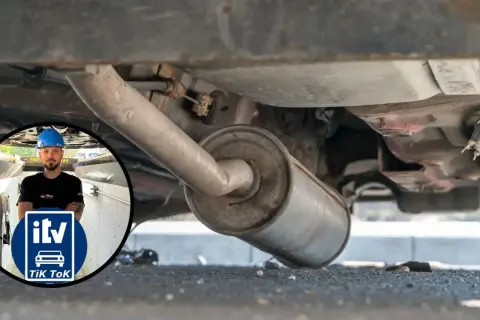 Inspección del tubo de escape de un coche. Un mecánico con casco azul supervisa la revisión.