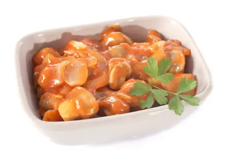 Un plat de champignons à la grecque, tendres et savoureux, baignant dans une sauce tomate onctueuse, garni d'une touche de persil frais.