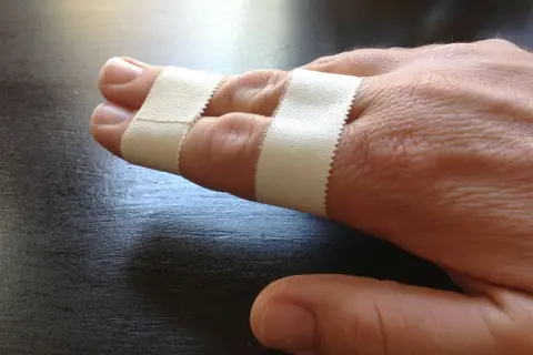 Zwei Finger sind mit Pflaster verbunden, um sie zu stabilisieren. Das Finger tapen hilft bei der Heilung.