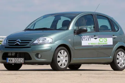 Zielony Citroen C3 z naklejką "Stop & Start" i informacją "W trosce o środowisko". Widać przednie żarówki.